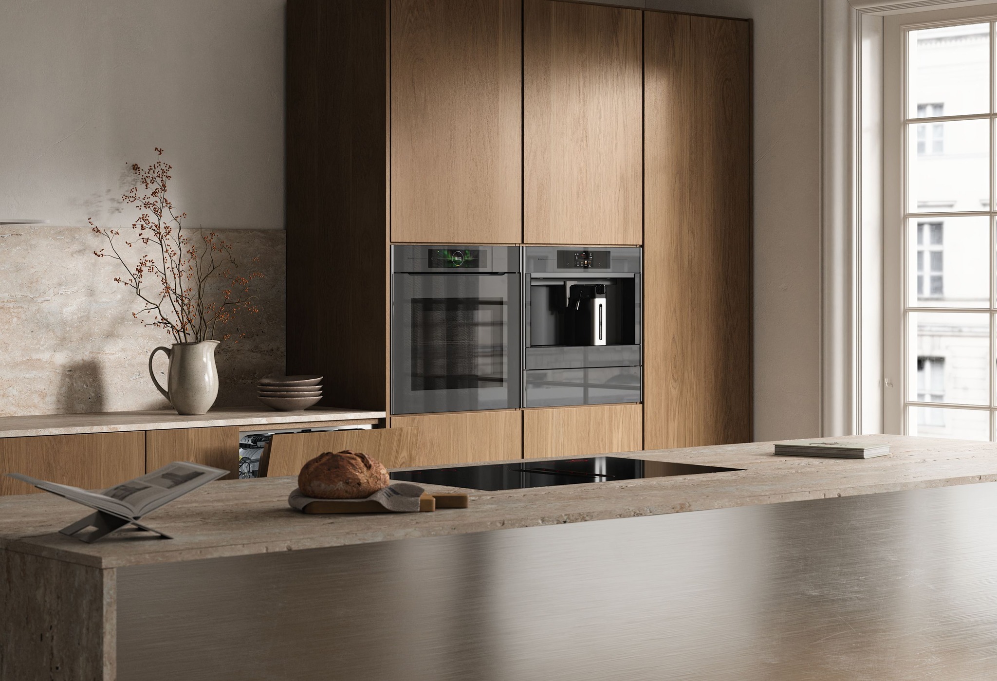 Modern kitchen with wooden cabinetry, built-in oven and coffee machine, a stone countertop island with a loaf of bread on a cutting board and an open cookbook on a stand.